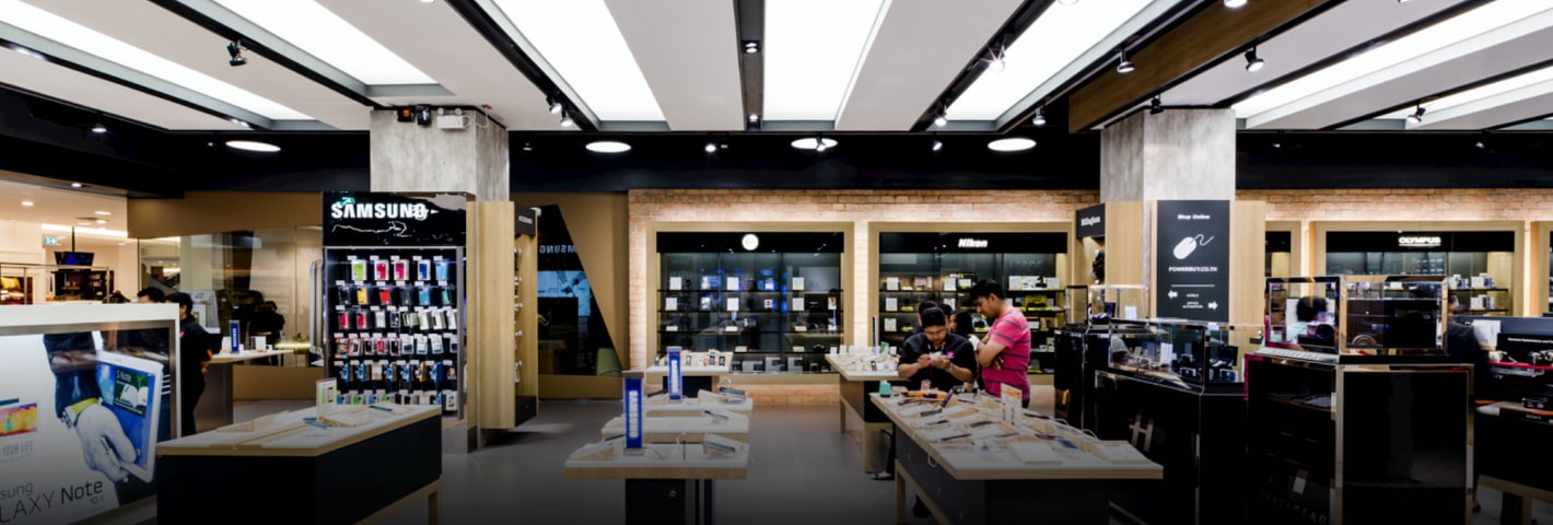 Modern electronics store interior featuring smartphone, camera, and accessory displays with customers browsing