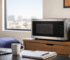 Best microwave for a dorm room or office on a tidy desk with a laptop, notebook, coffee mug, and indoor plant in a bright modern workspace.