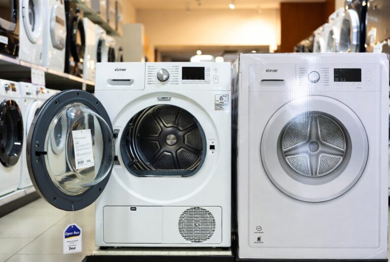 Open box electric dryer with open door next to a brand new boxed dryer at City Appliances